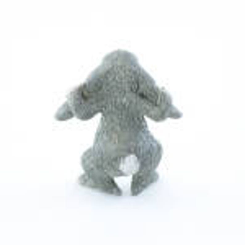 May include: A small, gray, ceramic rabbit figurine with a white tail. The rabbit is sitting with its ears up and its front paws raised.