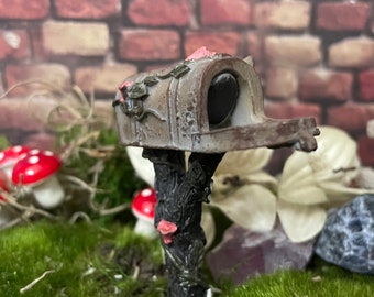 Adorable fairy garden mailbox on log post with vine of pretty pink and white flowers