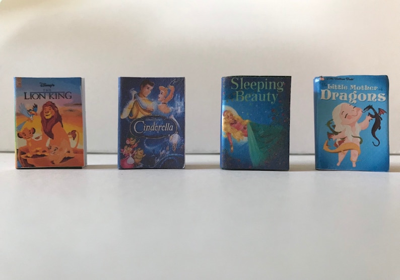 May include: Four miniature Disney storybook covers featuring The Lion King, Cinderella, Sleeping Beauty, and Little Mother Dragons. The covers are blue with colorful illustrations of the characters.