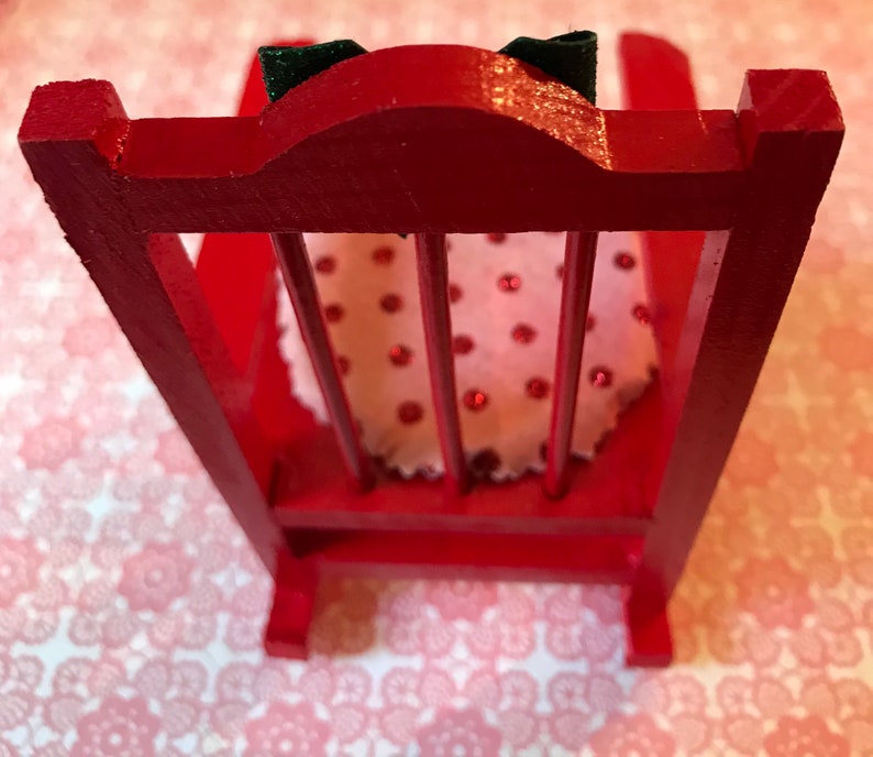 May include: A red wooden rocking chair with a white and red polka dot cushion. The chair has a high back and a simple design.