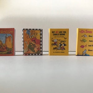May include: Four miniature hardcover books with colorful covers. The titles are "Robinson", "The Real Mother Goose", "But We Love You, Charlie Brown", and "One Fish, Two Fish, Red Fish, Blue Fish" by Dr. Seuss.