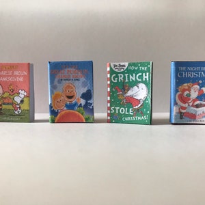 May include: Four miniature hardcover books with colorful covers. The books are titled "A Charlie Brown Thanksgiving", "It's the Great Pumpkin, Charlie Brown", "How the Grinch Stole Christmas!" and "The Night Before Christmas".