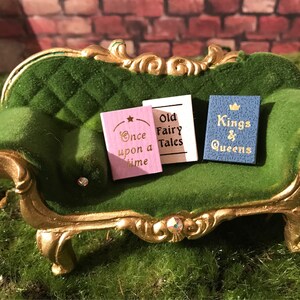 May include: Three miniature books on a green velvet couch. The books are titled "Once upon a time", "Old Fairy Tales", and "Kings & Queens".