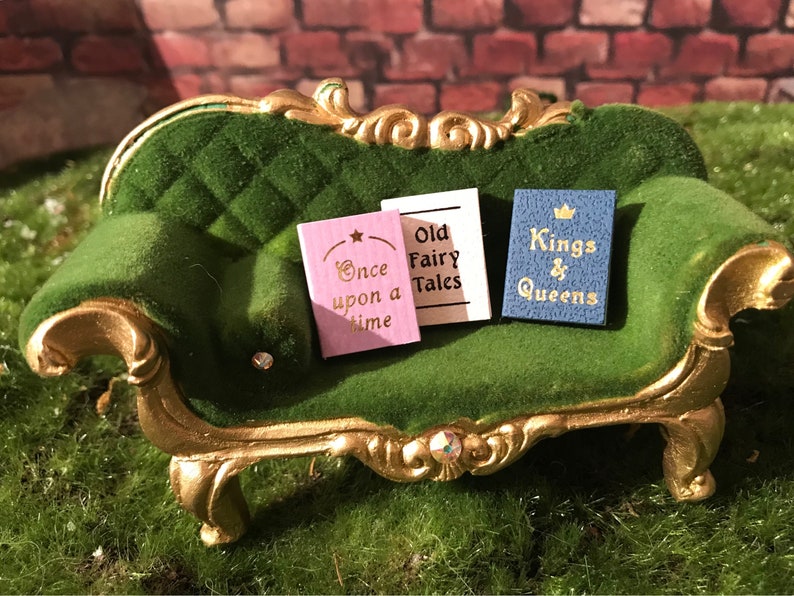 May include: Three miniature books on a green velvet couch. The books are titled "Once upon a time", "Old Fairy Tales", and "Kings & Queens".