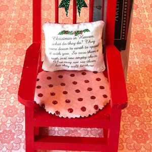 May include: A red rocking chair with a white cushion featuring the text "Christmas in Heaven, what do they do? They come down to earth to spend it with you. So save them a seat, just one empty chair. You may not see them, but they will be there." The chair has a pink and red polka dot cushion.