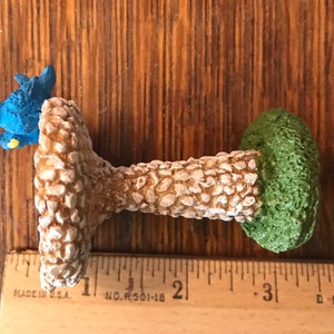 K&ouml;nnte beinhalten: Ein Miniatur-Vogelbad mit zwei blauen V&ouml;geln, die auf dem Rand sitzen. Das Bad ist aus einem strukturierten Material, das Stein &auml;hnelt, und hat eine gr&uuml;ne Basis.