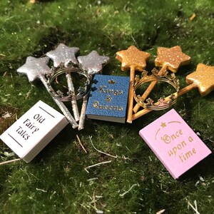May include: A set of miniature fairy tale themed items, including three gold star wands, two silver star wands, a gold crown, and four small books with titles "Old Fairy Tales", "Kings & Queens", "Once Upon a Time", and a fourth book with an illegible title.