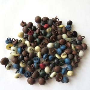 May include: A large collection of small, round buttons in various colors including brown, blue, white, black, and red. Each button features a smooth, matte surface and a small metal loop on the back for attachment, scattered in a dense pile.
