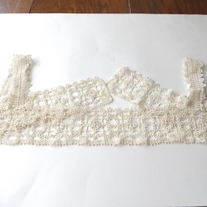 May include: Off-white, delicate lace trim, possibly vintage, arranged on a white surface. The lace features intricate floral and geometric patterns, with scalloped edges. The trim is likely for sewing or crafting projects.