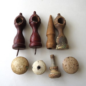 May include: A collection of vintage wooden hardware pieces, including finials, knobs, and curtain rod holders. The pieces are in various shades of brown and beige, with signs of wear and age.
