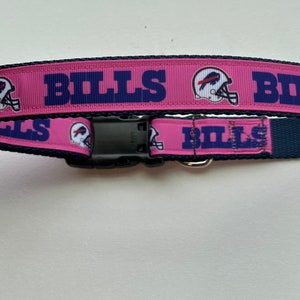 May include: Pink dog collar with a blue and white Buffalo Bills logo and the word "BILLS" repeated on the collar.