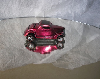 May include: A vintage red toy car with a black roof and chrome wheels. The car is a 1930s Ford Coupe.