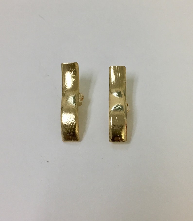 Peut inclure: Une paire de boucles d'oreilles clips dor&eacute;es avec un design ondul&eacute; textur&eacute;.