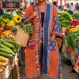 May include: A long-sleeved, open-front duster coat featuring a patchwork design with vibrant orange, blue, and yellow geometric and floral patterns. The garment includes two large front pockets and a quilted texture throughout the fabric.