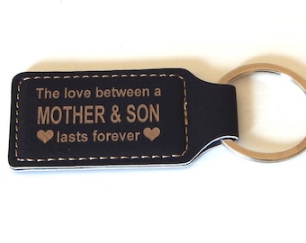 Op de afbeelding: Zwarte leren sleutelhanger met een zilveren sleutelring. De sleutelhanger heeft de tekst "The love between a MOTHER & SON lasts forever" met twee kleine hartjes.