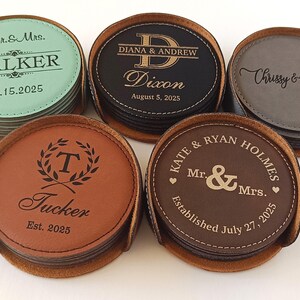 May include: Set of six personalized leather coasters with different names and dates. The coasters are brown, black, and gray. Each coaster has a different design, including a monogram, a heart, and a wreath.