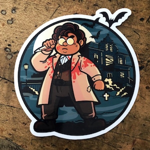 May include: A round sticker featuring a cartoon character in a blood-splattered coat, holding a knife. The background shows a haunted house, bats, and a full moon, creating a spooky Halloween theme. The sticker has a white border.