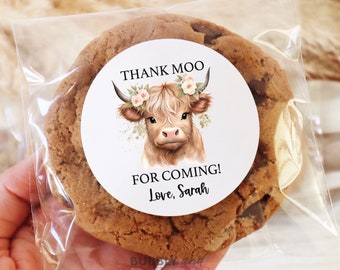 May include: A round sticker featuring a cartoon illustration of a Highland cow wearing a floral crown. The sticker reads "Thank Moo" and "For Coming! Love, Sarah".