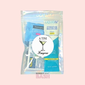 May include: A clear plastic bag filled with various items for a hangover kit. The items include a makeup remover towelette, a packet of electrolyte powder, a small tube of hand sanitizer, and a small bottle of liquid IV hydration multiplier. The bag also includes a round sticker with a martini glass and the text "A TINI Hangover".
