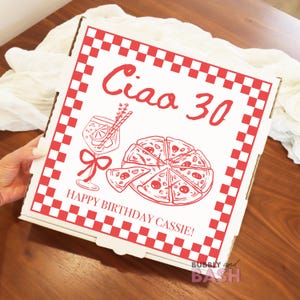 May include: A white pizza box with a red checkered border and red text that reads "Ciao 30" and "Happy Birthday Cassie!". The box features illustrations of a pizza, a cocktail, and a bow.