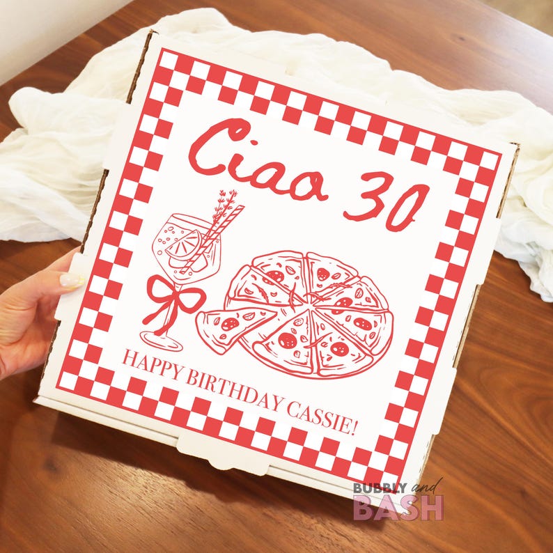 May include: A white pizza box with a red checkered border and red text that reads "Ciao 30" and "Happy Birthday Cassie!". The box features illustrations of a pizza, a cocktail, and a bow.