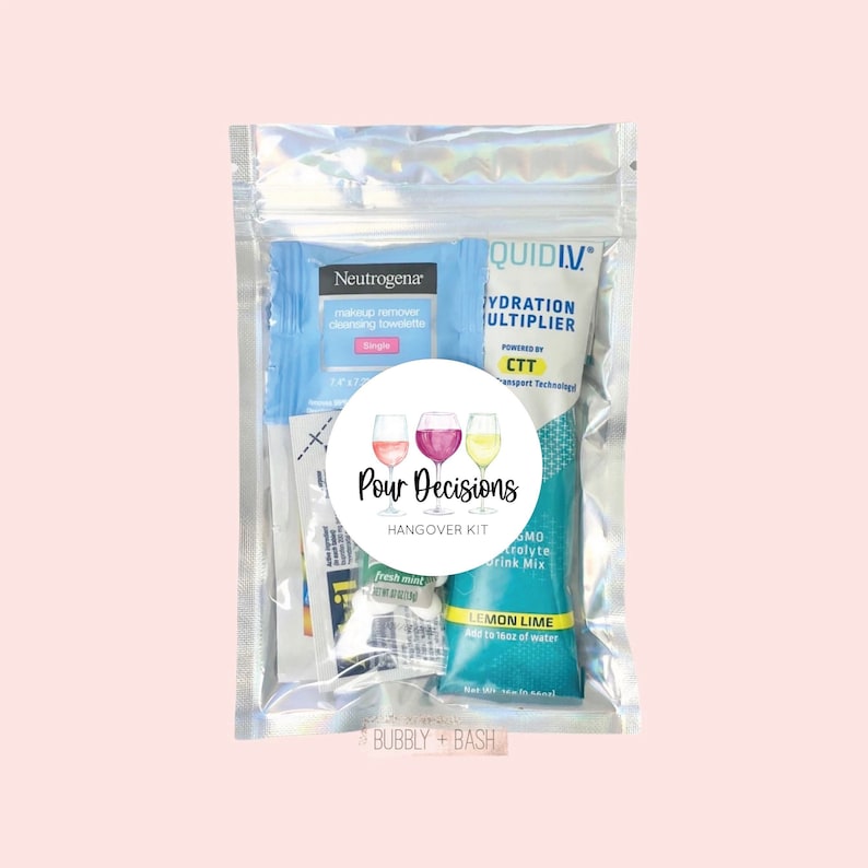 May include: A clear plastic bag with a white circle sticker that says "Pour Decisions Hangover Kit" with three watercolor wine glasses. The bag contains a small packet of makeup remover towelettes, a small packet of fresh mint gum, and a small packet of lemon lime electrolyte drink mix.