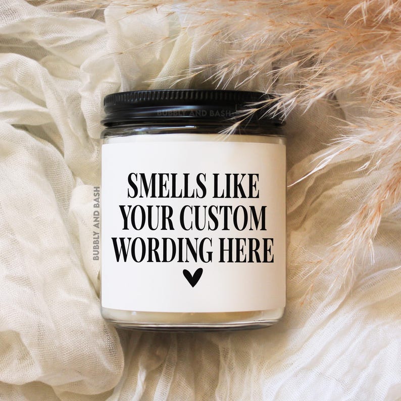 May include: White candle with a black lid and a label that reads "Smells Like Your Custom Wording Here" with a small heart symbol.