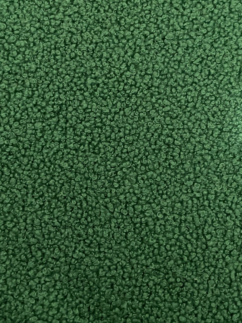 K&ouml;nnte beinhalten: Nahaufnahme eines dunkelgr&uuml;nen, flauschigen Stoffes. Der Stoff hat eine weiche, pl&uuml;schige Textur.