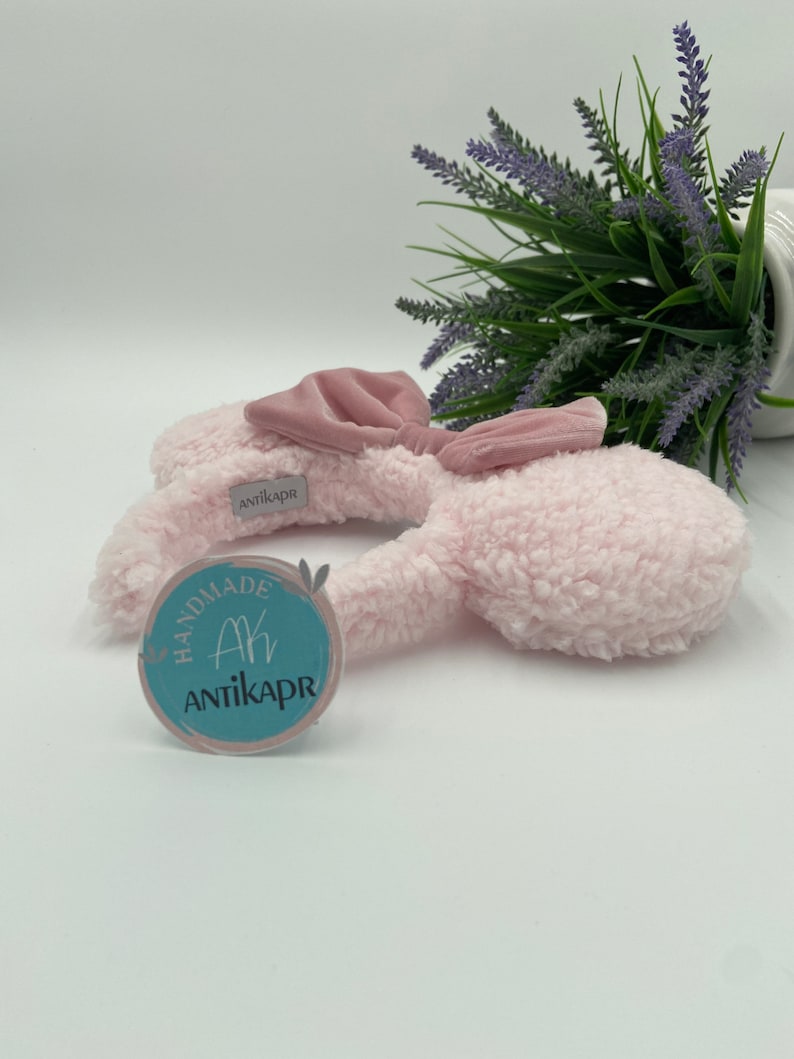 May include: Pink fluffy bunny ear headband with a pink satin bow. The headband has a handmade tag with the text "Ak Antikapr" on it.