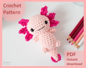 Peut inclure: Un jouet en crochet axolotl amigurumi rose avec des branchies roses. Le jouet est posé sur une surface blanche. Le texte "PDF téléchargement instantané" est dans le coin inférieur droit de l'image.