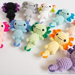 May include: A collection of 10 crocheted axolotl plushies in various colours, including pink, blue, green, yellow, orange, purple, white, grey, and black. Each axolotl has a unique colour combination and features a cute, smiling face.