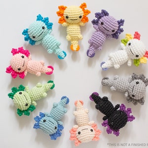 May include: A collection of ten crocheted axolotl plushies in various colours, including pink, blue, green, yellow, white, grey, and purple. Each axolotl has a unique colour combination and features a cute, smiling face.