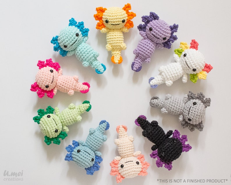 May include: A collection of ten crocheted axolotl plushies in various colours, including pink, blue, green, yellow, white, grey, and purple. Each axolotl has a unique colour combination and features a cute, smiling face.