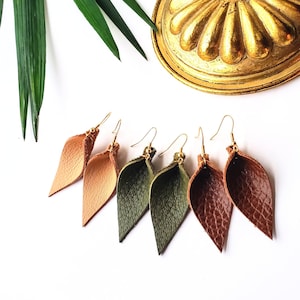 May include: Three pairs of leather earrings in the shape of leaves. The earrings are in shades of brown, tan, and green.