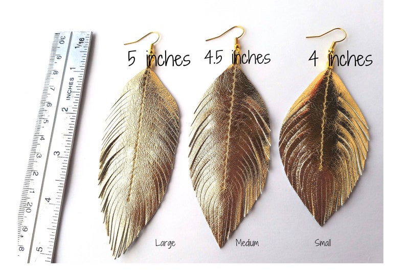 May include: Three pairs of gold leather feather earrings in different sizes: 5 inches, 4.5 inches, and 4 inches. The earrings are labeled "Large", "Medium", and "Small".
