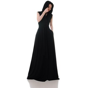 May include: A black maxi dress with a hood and a wrap-style neckline. The dress has a belt at the waist and is made of a soft, flowing fabric.