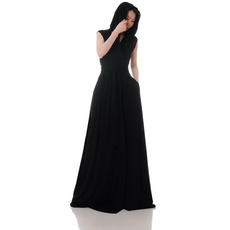 May include: A black maxi dress with a hood and a wrap-style neckline. The dress has a belt at the waist and is made of a soft, flowing fabric.