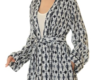 May include: A long-sleeved robe with a tie belt, featuring a white and navy blue tie-dye pattern. The robe has a V-neck and black piping around the edges.