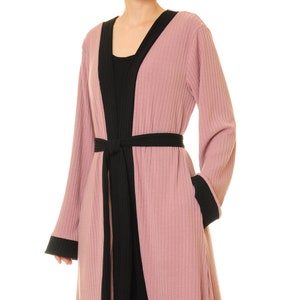 May include: A long-sleeved pink robe with black trim and a black sash. The robe has a ribbed texture and a V-neck.