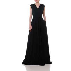 May include: A long, black sleeveless maxi dress with a V-neckline and a self-tie sash at the waist.