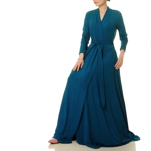 May include: A teal blue wrap dress with long sleeves and a self-tie sash. The dress is made of a soft, flowing fabric and has a relaxed fit.
