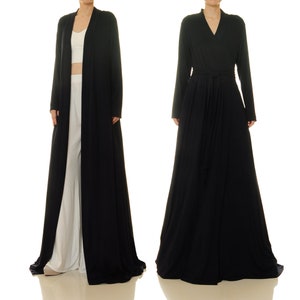 K&ouml;nnte beinhalten: Eine lange schwarze Robe mit V-Ausschnitt und Bindeg&uuml;rtel. Die Robe ist aus einem weichen, flie&szlig;enden Stoff gefertigt und hat lange &Auml;rmel.