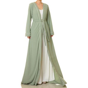 May include: A long, sage green robe with a white trim and a matching sash. The robe is open in the front, revealing a white undershirt.