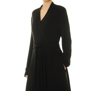K&ouml;nnte beinhalten: Ein schwarzes Wickelkleid mit langen &Auml;rmeln und einem Bindeg&uuml;rtel.