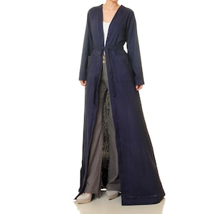 Könnte beinhalten: Ein langer, marineblauer Morgenmantel mit einem Bindegürtel und zwei Taschen. Der Morgenmantel ist vorne offen und zeigt eine graue Hose.