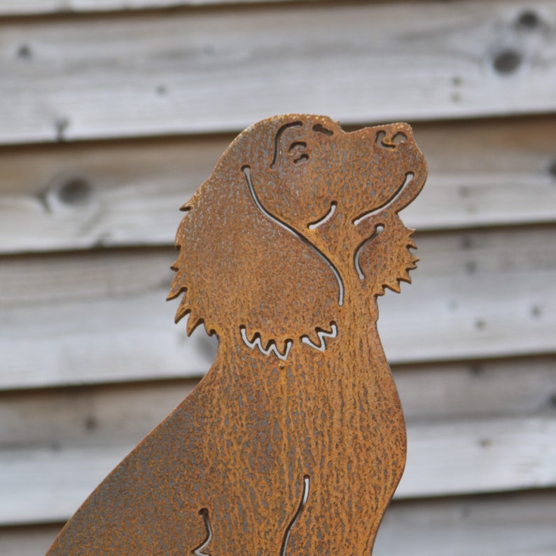 May include: A rusty metal sculpture of a dog, with a detailed outline of the dog's head and body. The sculpture is a silhouette of a dog, with a textured surface.