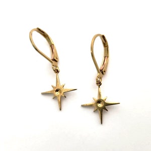 May include: A pair of gold star-shaped earrings with leverback closures.