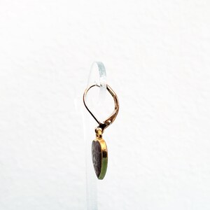 May include: Gold heart-shaped earring with a textured surface and a leverback closure.