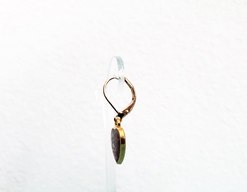 May include: Gold heart-shaped earring with a textured surface and a leverback closure.