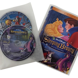May include: A two-disc DVD set of Disney's Sleeping Beauty Special Edition. The front cover features a colorful illustration of Princess Aurora and Prince Phillip kissing, with a dragon in the background. The back cover shows a close-up of the dragon and the text "2-Disc Set" and "Special Edition".